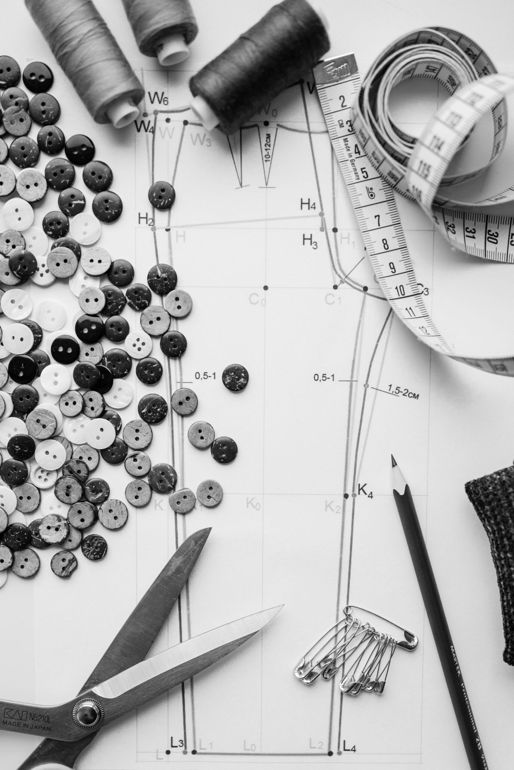 A black and white flatlay featuring sewing materials and tools on a sewing pattern.
